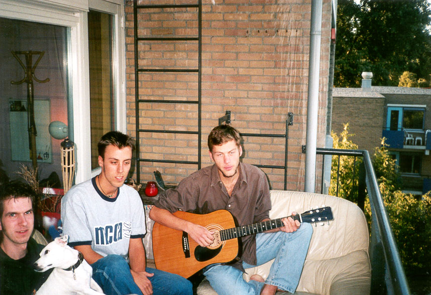 Three friends and a dog on a balcony, with an acoustic guitar